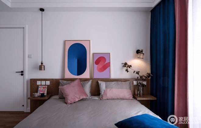 业主喜欢无床头的设计，但又需要一个护墙板，因为主卧的床和背靠都是现场定制的，所以，干脆将床头做成了柜式设计，可以陈列色彩丰富的简画，也因为黄铜吊灯让阅读更为方便；实木家具搭配灰色床品，却因为蓝色和粉色的窗帘，跳跃出了蓝粉时尚，满是温馨。