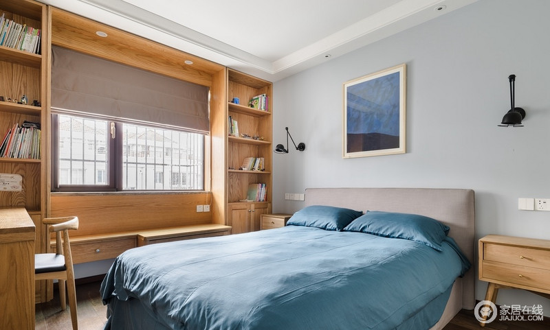卧室木质色的储物柜靠窗设置，足够实用，搭配蓝色的床品，床头用同色系的装饰画，整体空间简单温馨。