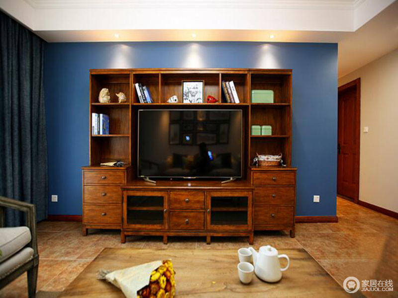 深色的木质电视柜提高了整个居家的复古美学，蓝色漆的墙面更是添置了不少时尚优雅。
