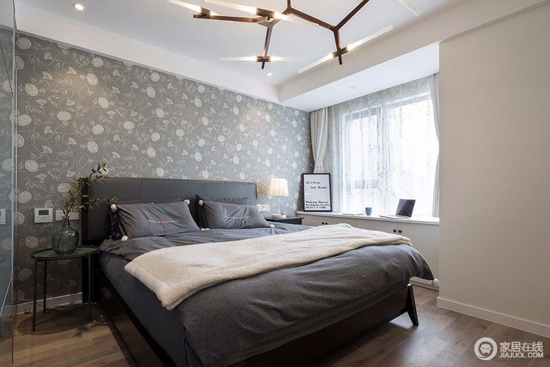 卧室在床头背景墙上，铺贴了灰色花卉墙纸，缤纷间衬托着黑灰色双人床，与其他墙面的白色形成视觉反差，制造出空间层次；树杈造型的吊灯，点缀出几分独特时尚。