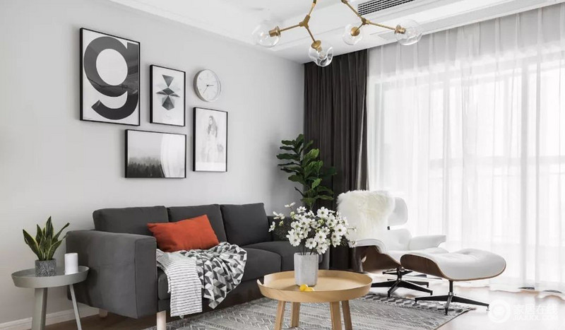 灰色布艺沙发搭配埃姆斯躺椅，圆形茶几与边几造型可爱，背景墙的错落装饰画与绿植盆栽装点空间。