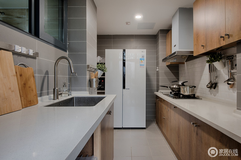 厨房线条简单，浅灰色墙面与米色地砖让整个空间的氛围格外柔和；米白色台面与实木橱柜温实的质地和自然的色调，构成简约和轻和，让生活毫无压抑感。