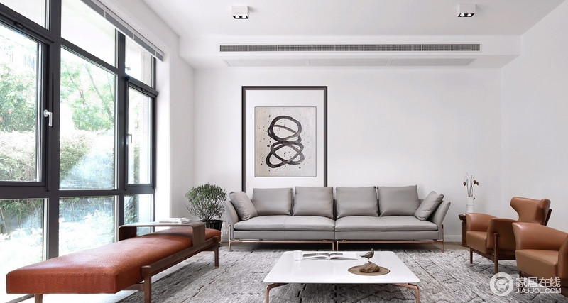 客厅整体颜色十分和谐，原木色地板搭配简约风的灰色和棕色沙发，给予生活素雅之余，搭配灰色地毯、白色茶几和一副简画，让空间及简单又素雅。