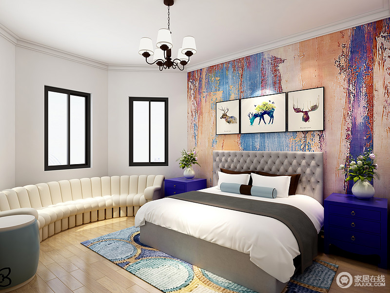 卧室虽然以白色为主，但是彩色背景墙的油画质感，让空间充斥着艺术的味道；因为空间结构环状设计，所以白色沙发配套呈现，发挥了空间性，同时，搭配灰色纽扣床头，流动着些许古典之美；紫色床头柜搭配蓝绿色系的几何地毯，给家带来色彩与摩登。