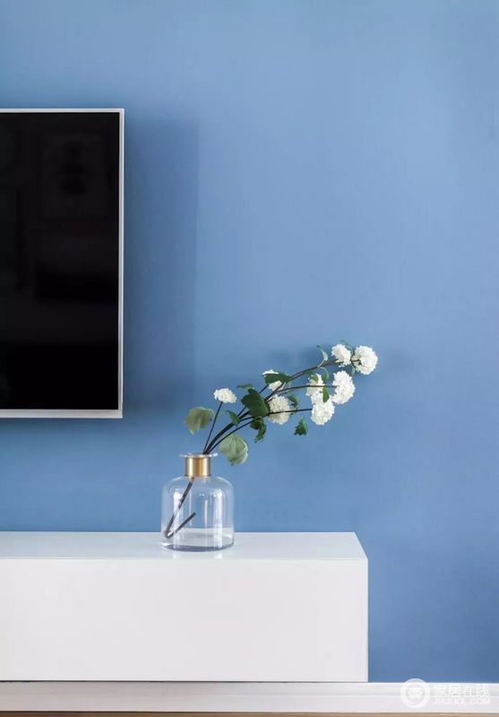 蓝色电视背景墙，木作架空白色电视柜，呈现简约氛围。