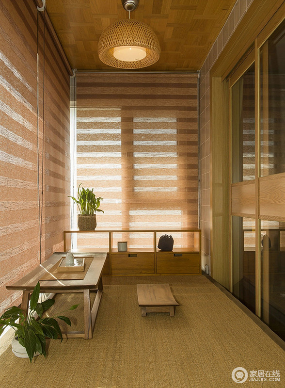设计师把卧室的阳台设计为一个飘窗式的休息区，卷帘的条纹设计既简单又起到了遮阳效果；新中式木柜和实木茶几、小凳营造了一个禅静的格调，朴素中更为静谧。