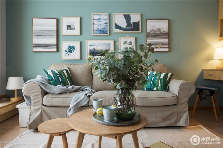 浅驼色的布艺沙发，因为绿色的沙发背景墙和植物元素的靠垫少了枯燥；墙面上的一组组简画，既可以起到装饰的作用，又与北欧圆几、绿植构成生活的清新。