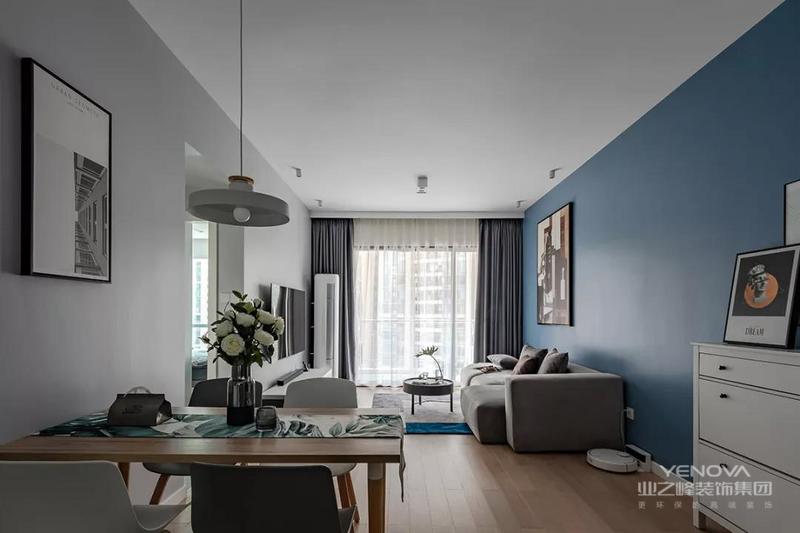 客厅在灰色电视墙+蓝色沙发墙，搭配木质地板，整体简约自然的家具布置，营造出一种现代轻松的大气。
