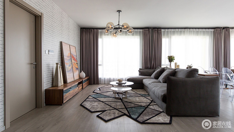 客厅运用几何图形地毯与灰度沙发的搭配，在视觉上具有下沉的作用，提升了整体空间的格调品味