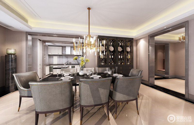 餐厅与半开放式的厨房相连，高级灰镶钻皮质餐椅散发着深邃与优雅，与黑色餐桌相配，带入空间一丝霸气稳重的魅力。鎏金色的灯具与酒柜上的描金线条，则添置一份奢华。