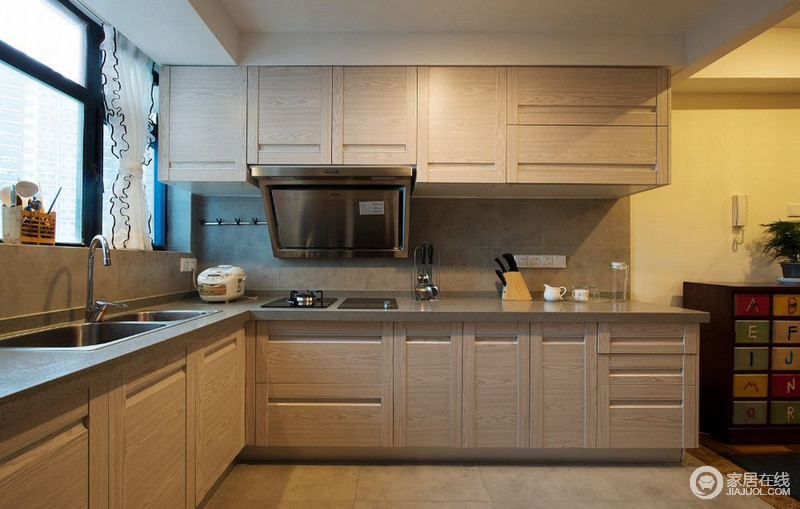 开放式的厨房以L型布置设计，使空间拥有足够的存储空间，同时加强了空间上的沟通便利。原木色的整体橱柜，搭配冷硬的金属台面，呼应了空间的主题风格。