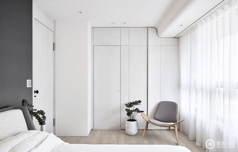 卧室看似简单，却也不简单，设计师巧妙地将衣帽间嵌于墙体内，通过原木门和板材打造出空间的流畅感，简约木椅与盆栽营造了生活的小惬意，实用之余更为温馨。