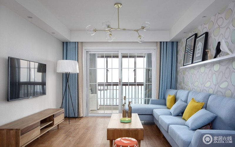 空间以白色为底，而植物元素的壁纸增加了空间的清和，蓝色沙发、窗帘在黄色靠垫和北欧风落地灯的点缀中，衬托着原木家具的简素和实用，让生活更为舒适。