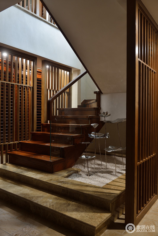 木结构的楼梯更显出木屋的质感，转角的银色金塑饰品仿似荷花，将泽明趣意绽于空间；两侧木格栅让空间的空隙变得愈加疏密有度，质感超脱。