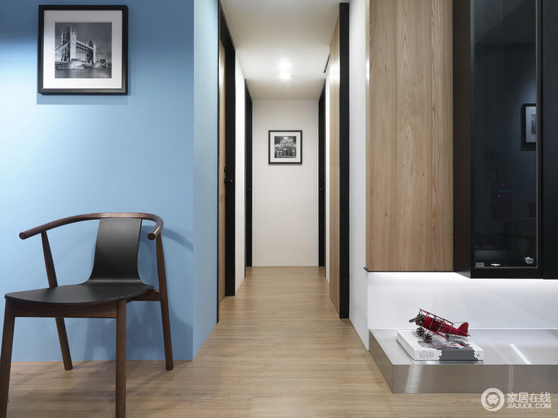走廊的墙面色彩很鲜明，蓝色的幽蓝因为黑白画作而时尚不少，新中式简约的单椅带来中式素雅；而实木悬挂柜的的悬空感，与实木地板呈自然之态，让你在简约中感受自然温实。